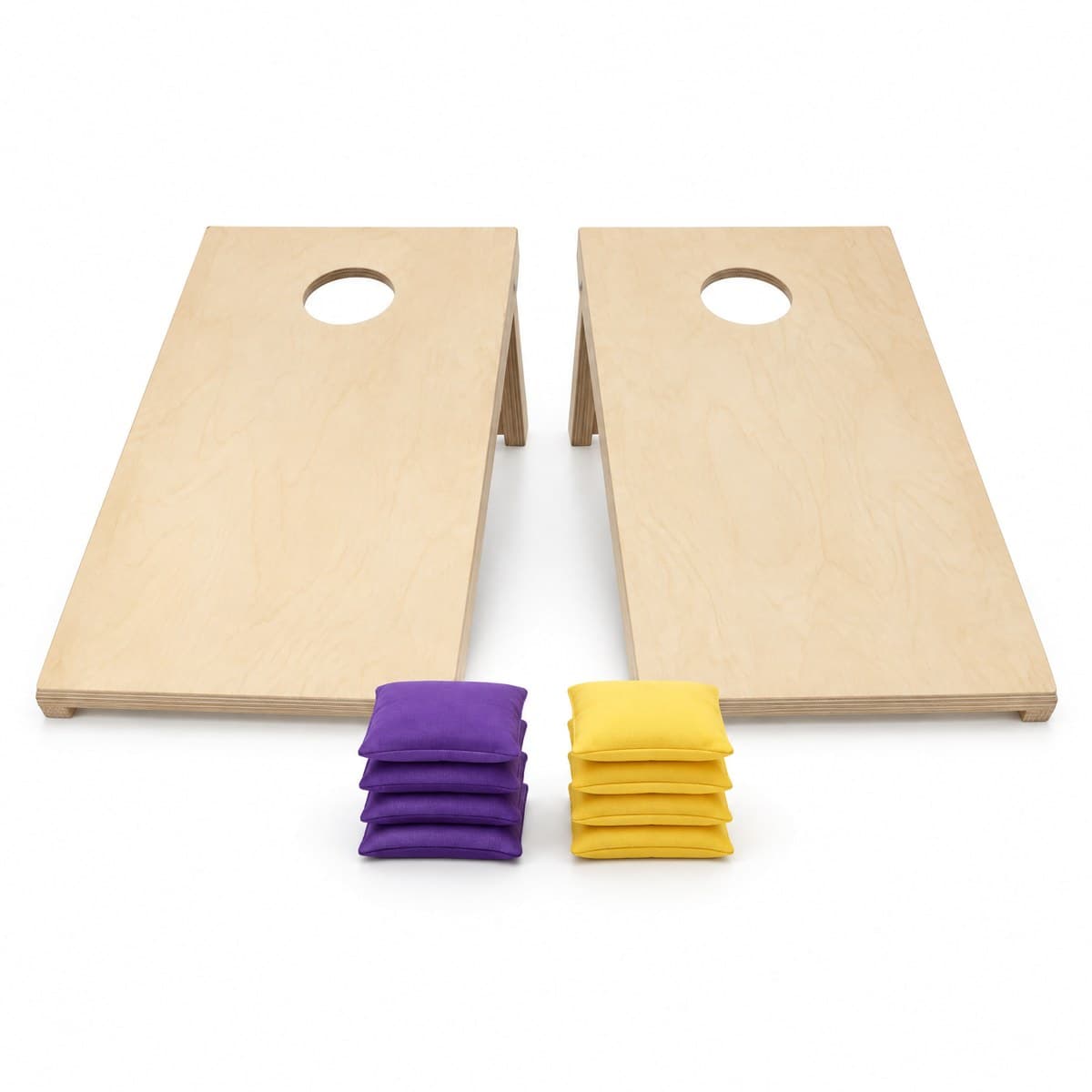 Two birch cornhole boards with a round hole in each, with a stack of four purple and a stack of four yellow bean bags in front